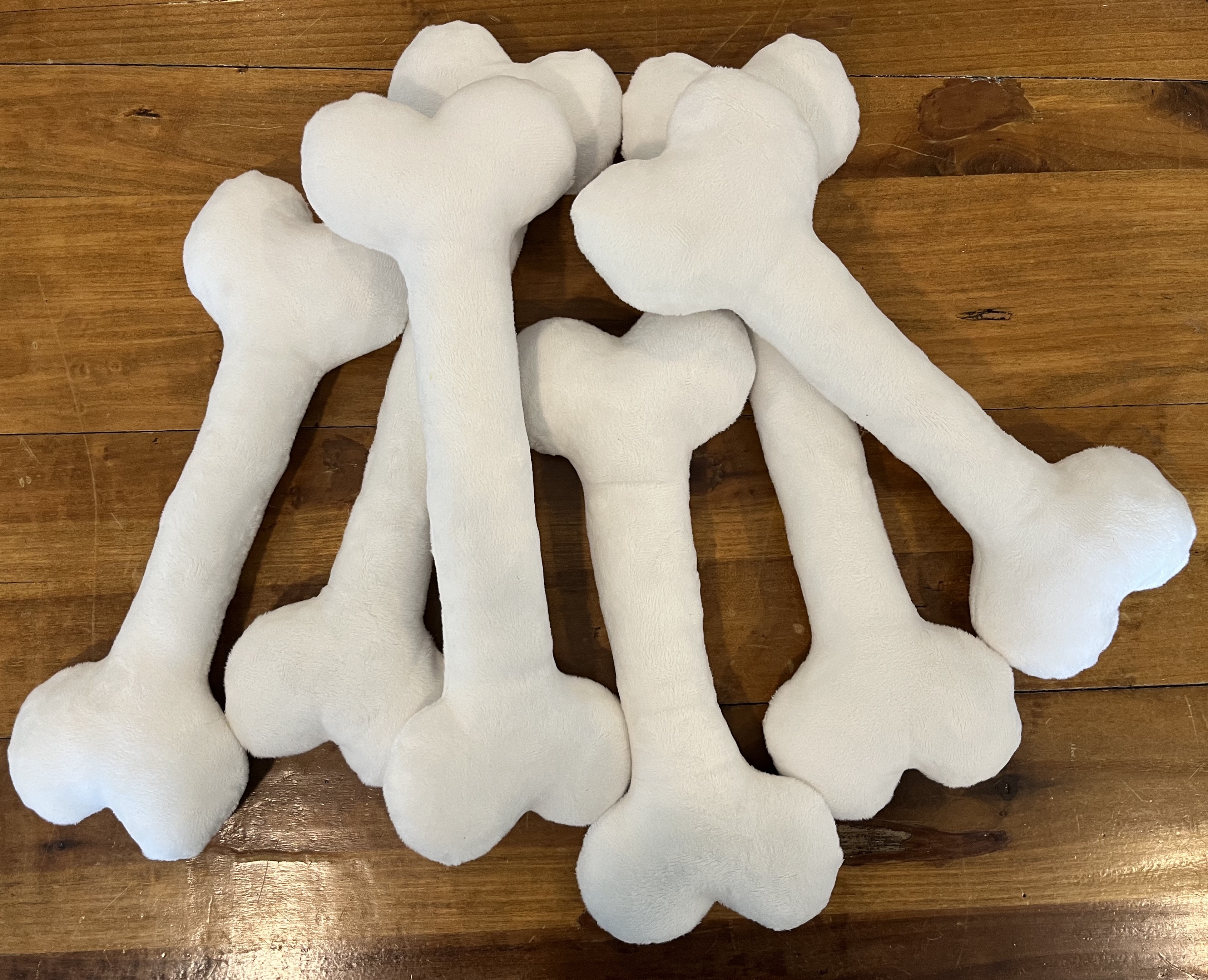 A pile of off-white plush bones laying on a wooden table