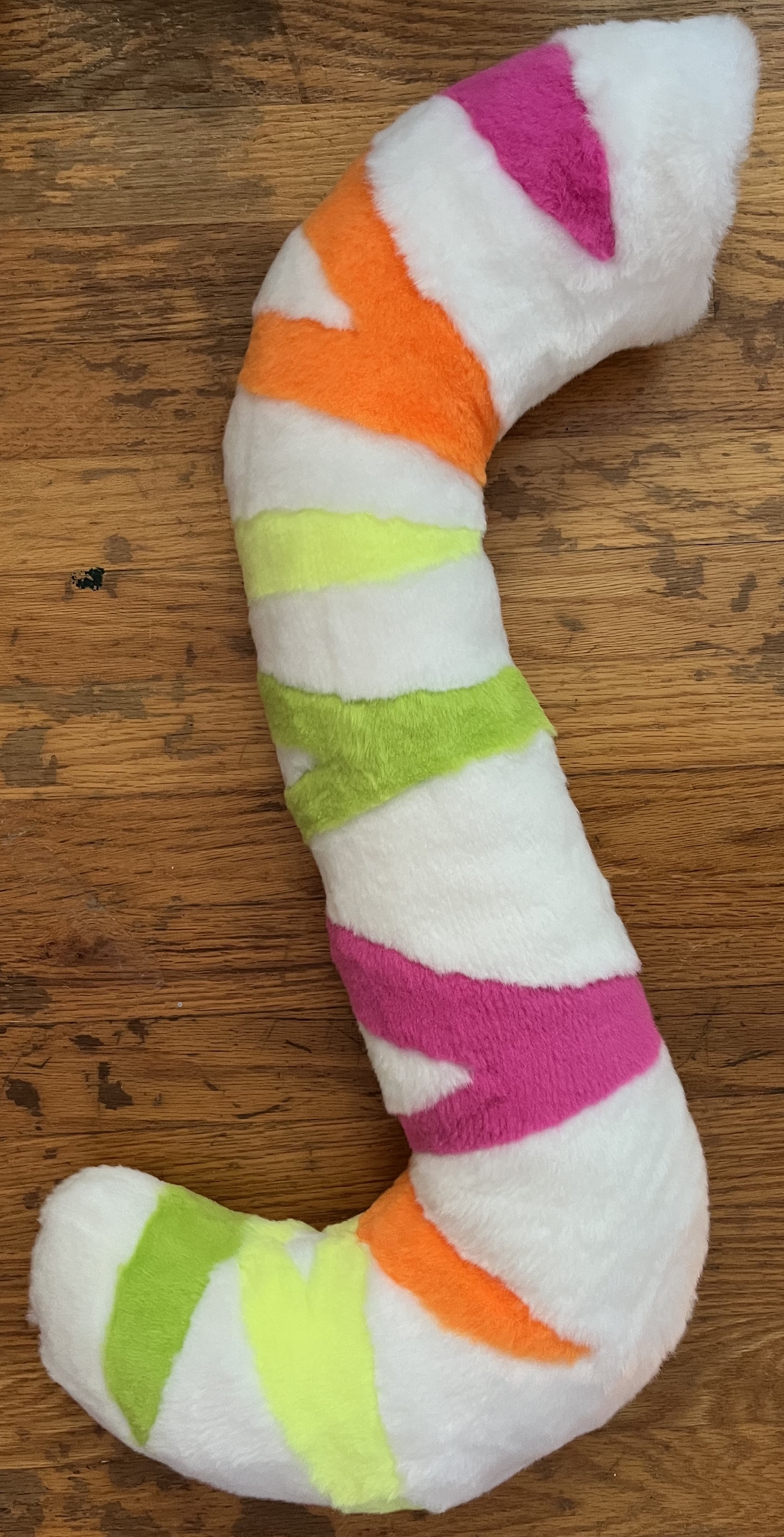 A long white fursuit tail with neon tiger stripes in pink, orange, yellow, and green alternating