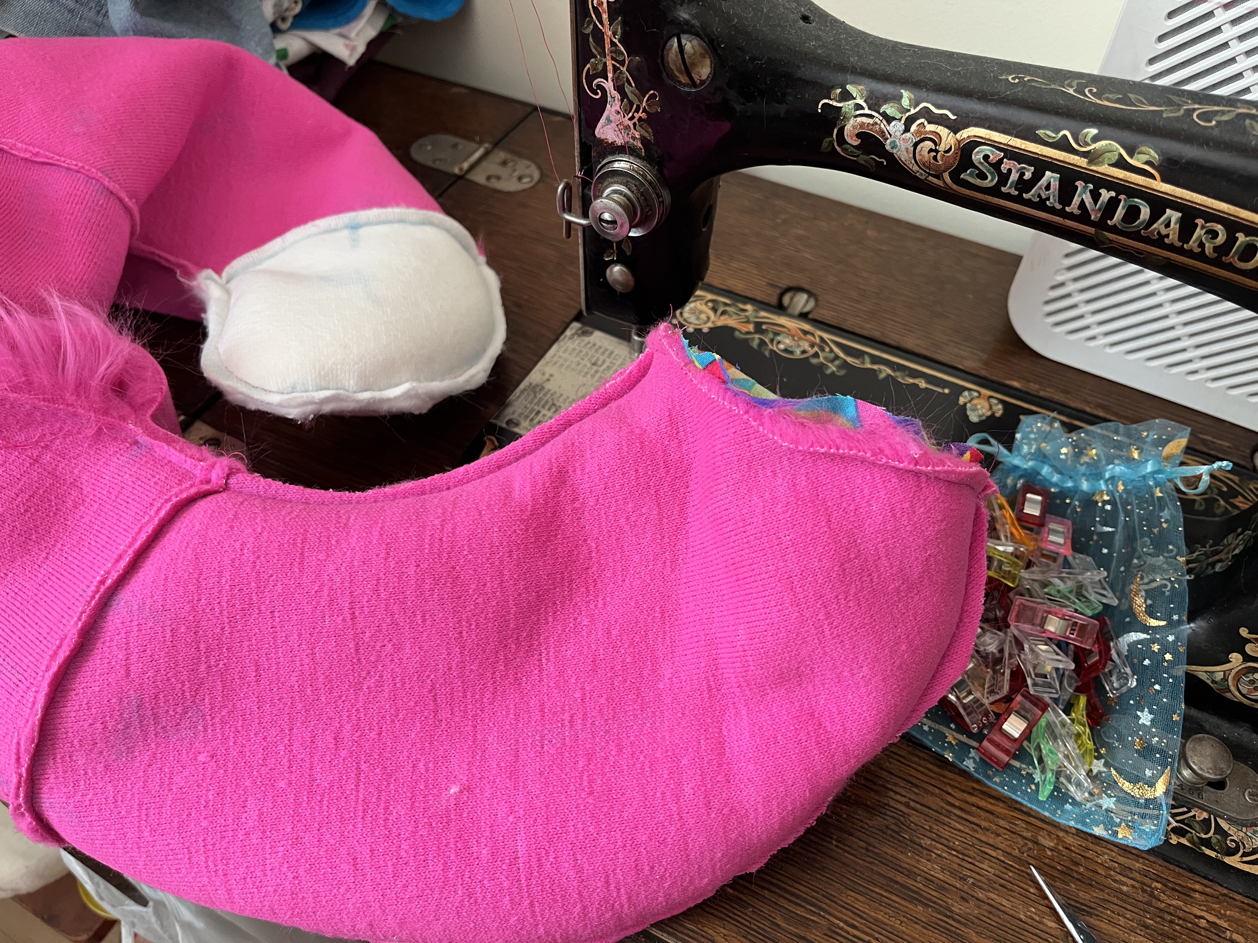 A long pink and white tail inside out, being sewn by a vintage sewing machine